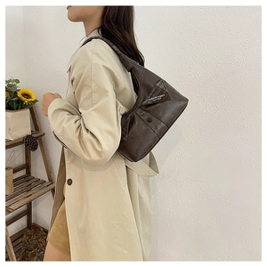 Close-up of a vintage coffee brown shoulder bag with triangle flap and knotted strap detail