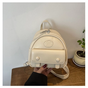 Detaillierte Nahaufnahme der Vordertasche und Fashion-Prägung des cremefarbenen Mini-Rucksacks