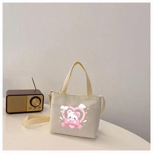 Detail of cute bear canvas shoulder bag with pink heart print on a warm beige background