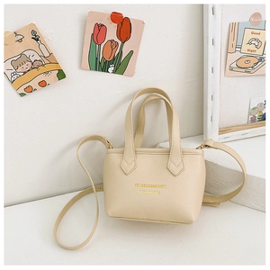 Détail du mini sac seau beige avec texture litchi et lettrage doré élégant imprimé