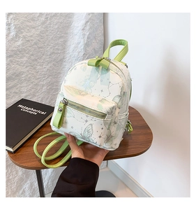 Mini-Rucksack mit grünem Schmetterlingsdruck auf Kunstleder auf einem runden Holztisch