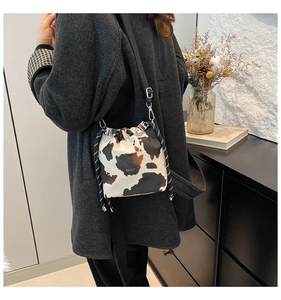 Dettaglio della borsa a secchiello maculata con scritta BAGS su una donna in cappotto grigio