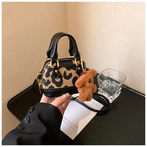 Détail du mini sac léopard avec garniture en cuir noir et breloque ours en peluche