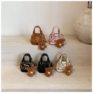 Cinq mini sacs en cuir assortis avec porte-clés ours en peluche sur un présentoir en pierre
