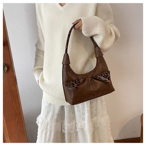 Detail of a brown leather shoulder bag featuring leopard print and button embellishments