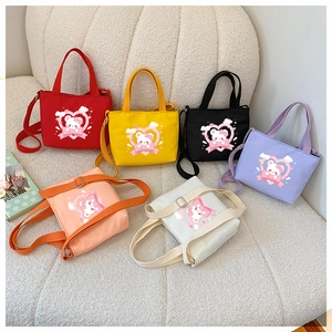 Detail of colorful canvas bear print tote bags with adjustable straps on a soft sofa