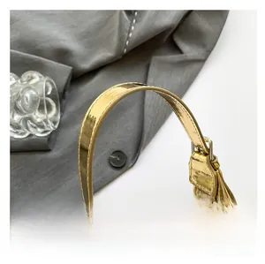 Detail of glossy gold handbag showing adjustable shoulder strap and smooth metal buckle