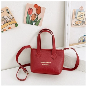 Détail du mini sac seau rouge en cuir grainé avec texte doré et bandoulière réglable