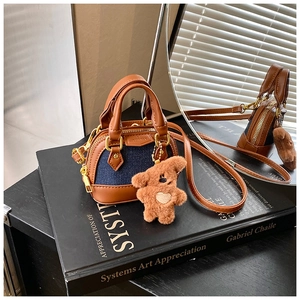 Close-up of mini denim shell bag with gold hardware and a cute plush bear charm