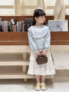 Girl wearing light blue heart sweatshirt and white tiered tutu skirt in cozy setting