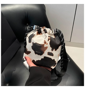 Dettaglio della mini borsa a secchiello con stampa mucca, coulisse e tracolla in tessuto