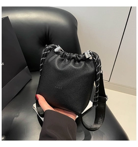 Dettaglio della borsa a secchiello nera con trama in pelle litchi e cordoncino intrecciato