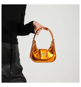 Close-up of bright orange metallic leather handbag with silver bow detail