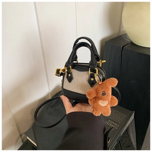 Detail of mini girl's tote bag featuring black leather, woven fabric and plush bear charm