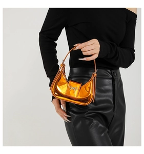 Macro shot of metallic orange mini handbag with a silver bow clasp and sleek handle