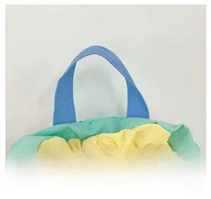 Close-up of durable sky blue woven handles on a green and yellow drawstring bag