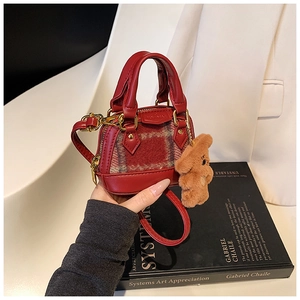 Close-up of red plaid mini handbag with plush bear charm and adjustable strap