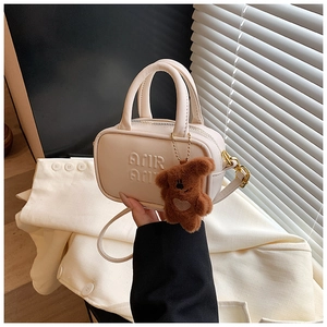 Detail view of mini off-white Boston bag with embossed letters and plush bear charm
