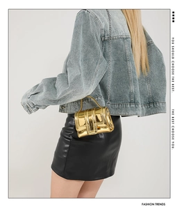 Gros plan d'un mini sac à main doré effet miroir avec une fine bandoulière chaîne