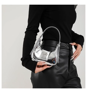 Detail of silver metallic mirror handbag with a stylish bow buckle on black clothing
