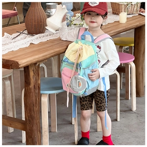 Detail view of kids color-block drawstring backpack with round mini pouch accessory