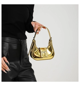 Detail of a mini golden bow handbag with metallic mirror finish and crescent shape