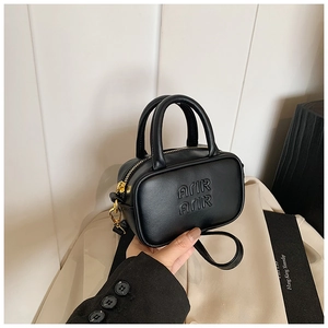 Close-up of mini black handbag with embossed lettering and gold-tone zippers
