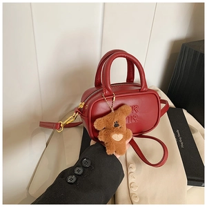 Deep red leather mini Boston bag with plush puppy charm and embossed letter detail