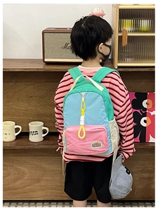 Detail of color-block kids backpack with yellow zipper pull and brand patch shown on model