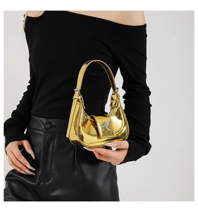 Close-up of metallic gold crescent bag with silver bow detail and sleek patent finish