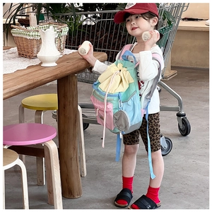 Toddler modeling a colorful multi-pocket drawstring backpack with a small round pouch