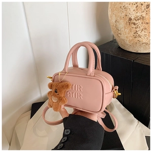 Detail of pink mini bowling bag with embossed lettering and brown teddy bear charm