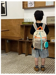 Detailed back view of a color-blocked canvas backpack for kids in a cozy cafe setting