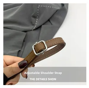 Détail d'une bandoulière réglable en cuir marron avec boucle argentée et couture fine