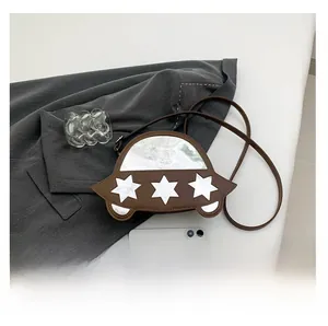 Détail d'un sac bandoulière marron en similicuir en forme de voiture avec étoiles blanches
