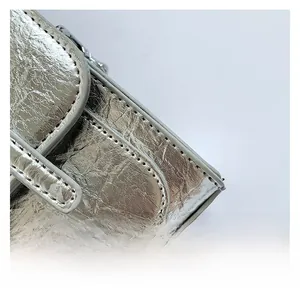 Macro shot of silver crinkled texture fabric and grey stitched edges on a mini crossbody bag