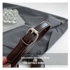 Close-up of adjustable dark brown faux leather shoulder strap with silver metal buckle