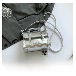 Mini silver metallic bag showing compact size compared to a smartphone with silver buckles
