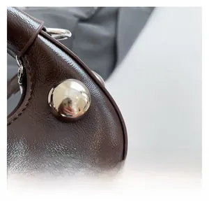 Close-up of coffee brown leather texture and large silver metal studs on the handbag