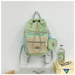 Lifestyle shot of green drawstring backpack with small pouch on white wall background