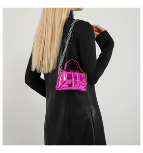 Vue détaillée du mini sac en cuir verni rose fuchsia porté par un mannequin en noir