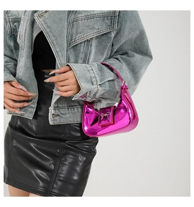 Detail of metallic magenta mini handbag with silver bow clasp on model with denim jacket