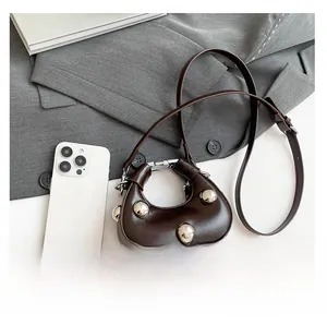 Detailed close-up of dark coffee crescent bag with silver studs and phone for scale