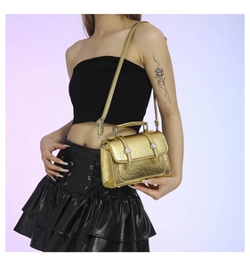 Close-up of golden metallic textured messenger bag with unique crinkled finish and silver buckles