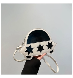 Détail du sac bandoulière blanc en forme d'OVNI avec étoiles noires et cuir poli brillant
