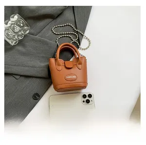 Nahaufnahme der braunen Mini-Eimertasche mit silberner Kugelkette und Litchi-Narbung