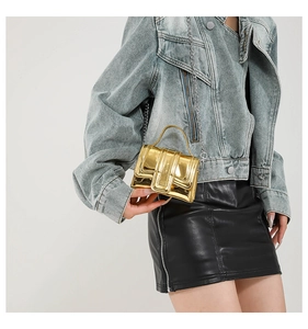 Détail d'un mini sac à main doré effet miroir avec bandoulière en chaîne pour femme