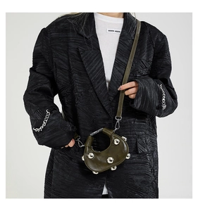 Detail of dark green crescent bag featuring large silver studs and metallic hardware