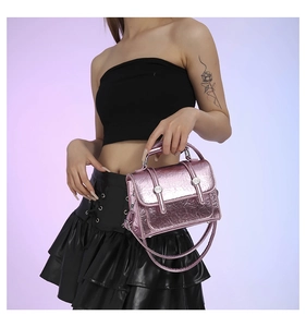 Detail of metallic pink wrinkled leather mini handbag with silver rivets worn by model