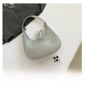 Detail of silver rhinestone hobo bag showing compact size compared to a smartphone